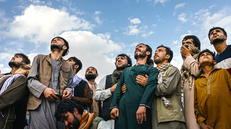 عزاداران در مراسم تشییع جنازه ده فرد کشته شده بر اثر حمله پهپاد آمریکایی در ماه اوت/آگوست، در حال تماشای هواپیماهای نظامی آمریکایی هستند.  