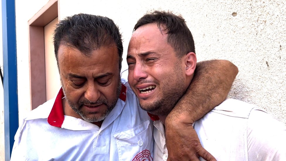 Mahmoud Al-Masry is comforted by a colleague after his father was killed, 11 October 2023