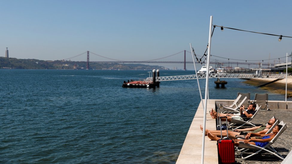 Tourists relax on the water's edge in Lisbon