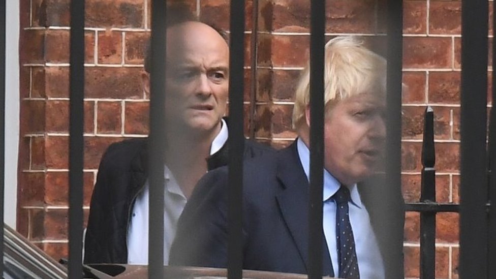 Dominic Cummings ve Boris Johnson ofislerinin arka kapısından çıkıyorlar, 2019