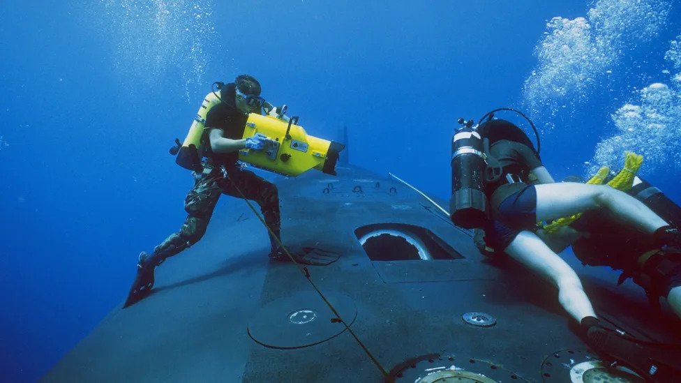 Buzos nadan cerca a un submarino
