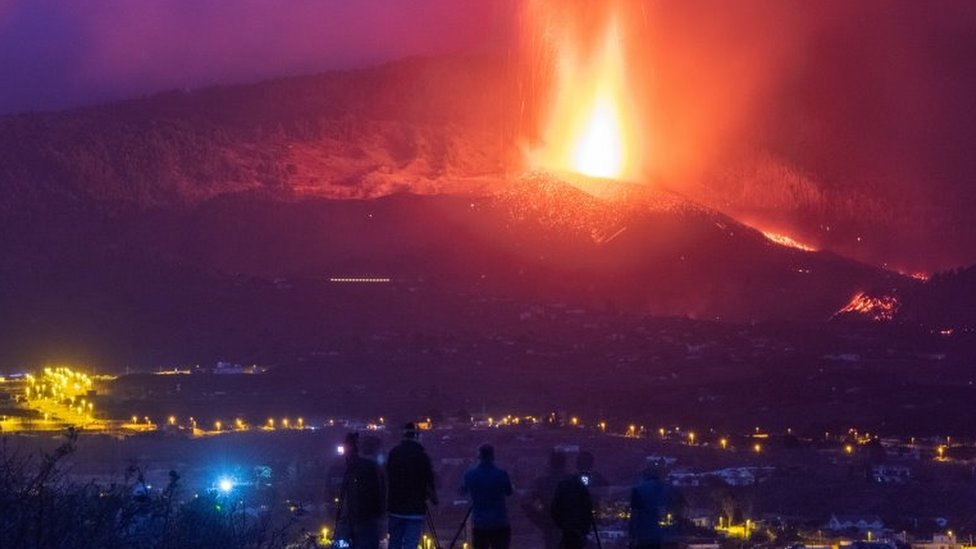 Lava and smoke are fired by the La Palma volcano as a group of people watch.