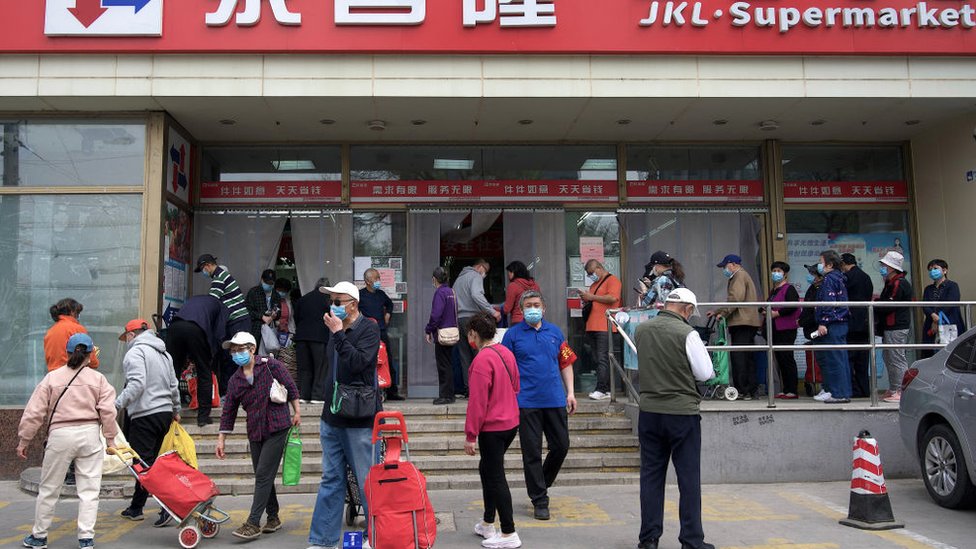 People crowd outside a supermarket in Beijing to get food