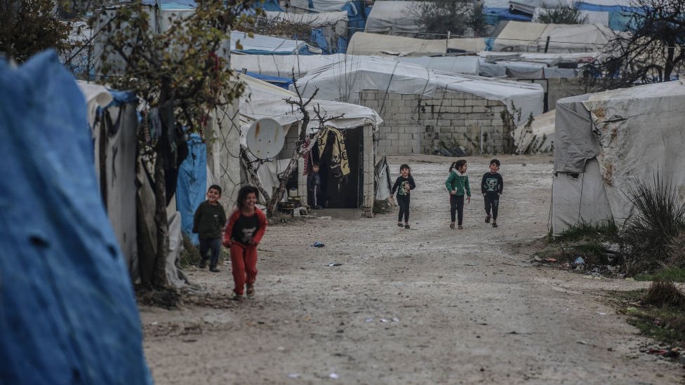 Niños caminan en el campo de refugiados de Idlib.