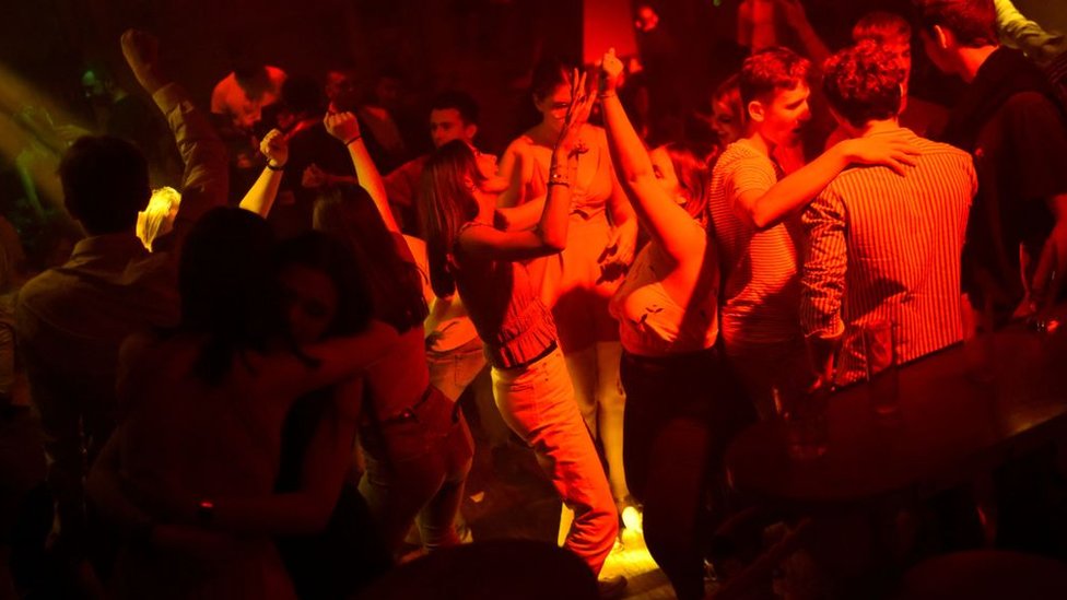 Jovens dançam em um clube noturno sob luzes vermelhas