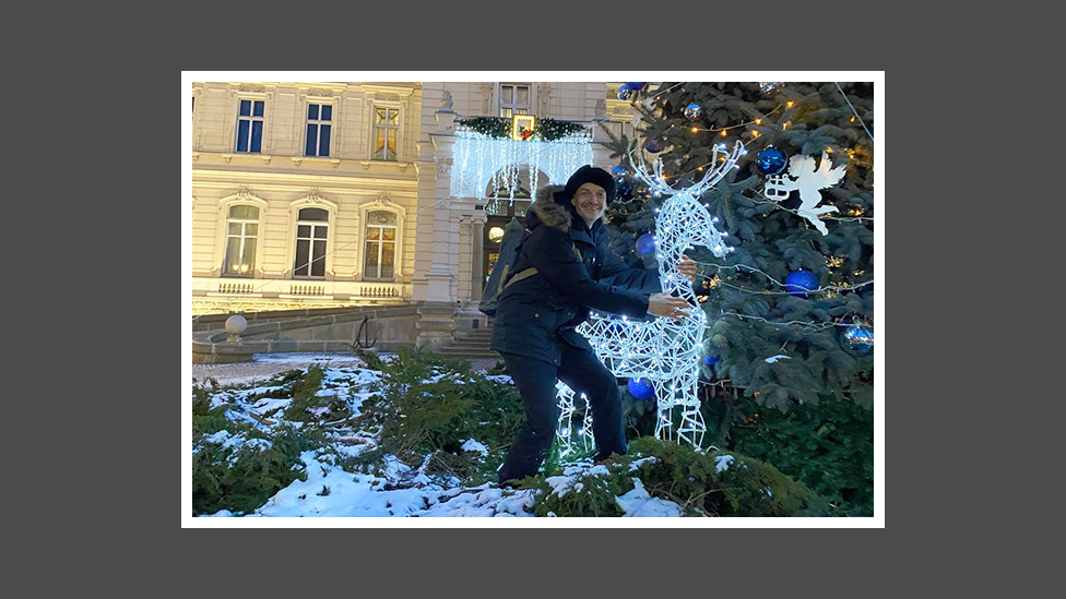 Andriy abraça uma rena decorativa do lado de fora da Galeria Nacional de Arte de Lviv