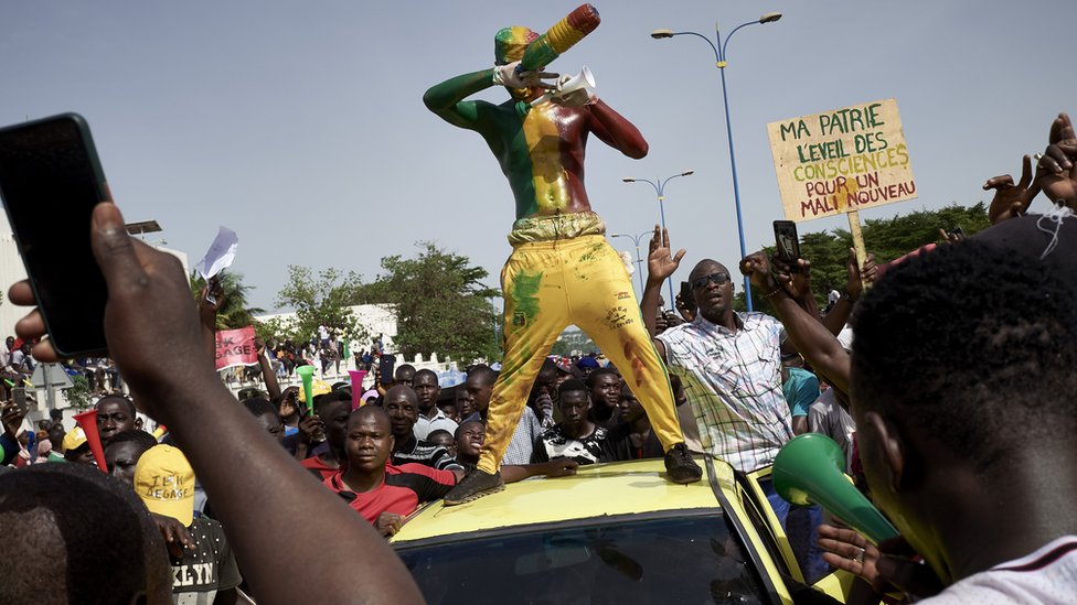 Мужчина, раскрашенный в цвета малийского флага, жестикулирует на площади Независимости, когда протестующие собираются, чтобы потребовать, чтобы президент Мали Ибрагим Бубакар Кейта покинул свой пост в Бамако 19 июня 2020 г.