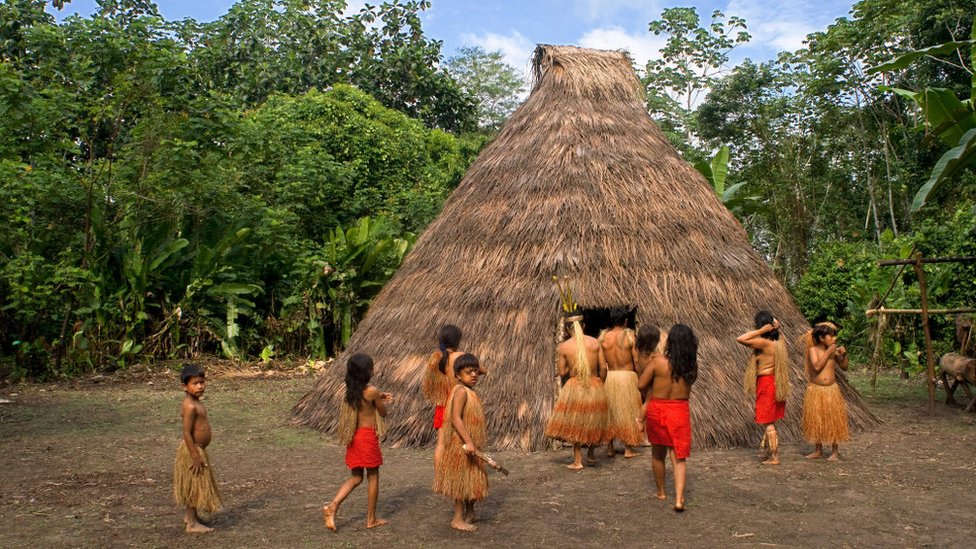 Indígenas junto a una choza en la selva amazónica.