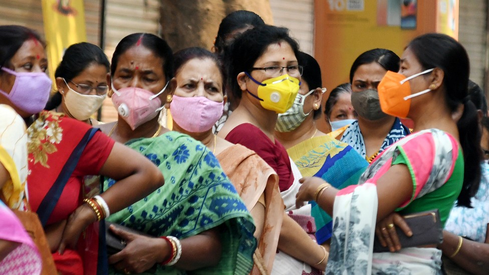 Mujeres en India con mascarillas hacen fila para recibir la vacuna covid