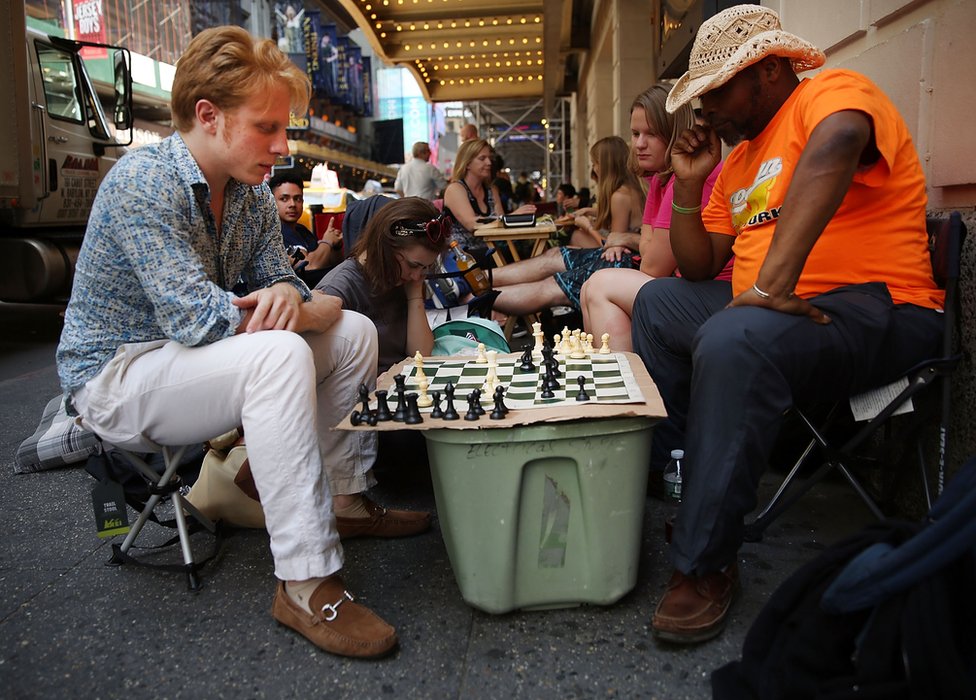 Люди, играющие в шахматы в очереди на получение обратных билетов в Гамильтон в Нью-Йорке в 2016 году