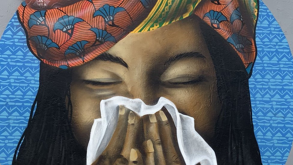 Mural en Senegal con una mujer sonándose.