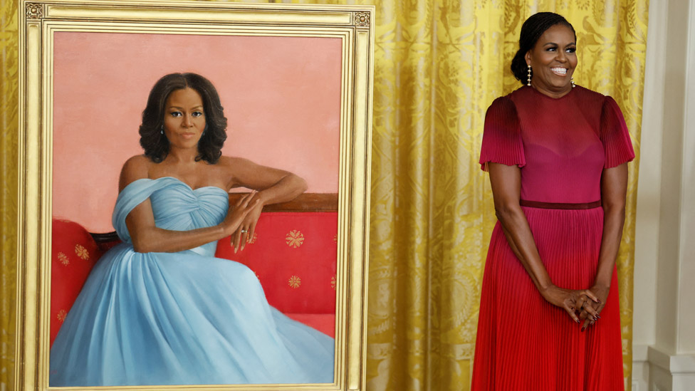 La exprimera dama de EE.UU. Michelle Obama posa al lado de su retrato oficial en la Casa Blanca, pintado por Sharon Sprung