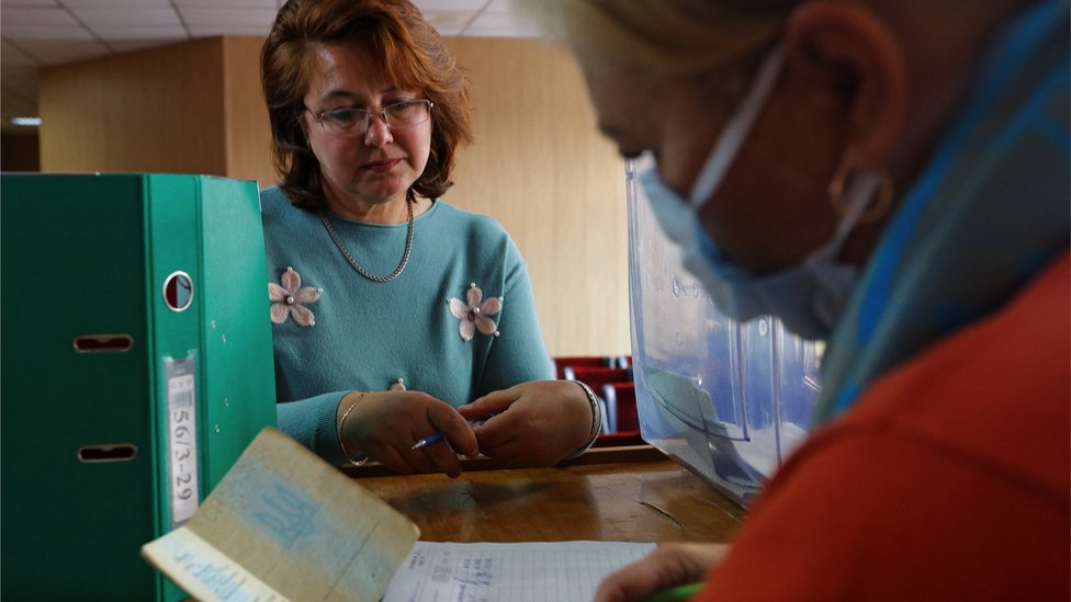 一名選舉官員在馬里烏波爾檢查一名婦女的護照，核實她的身份