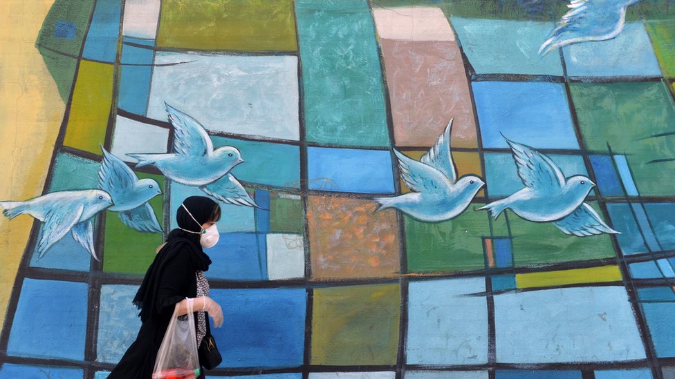 Иранская женщина проходит мимо яркой стены в столице Тегеране