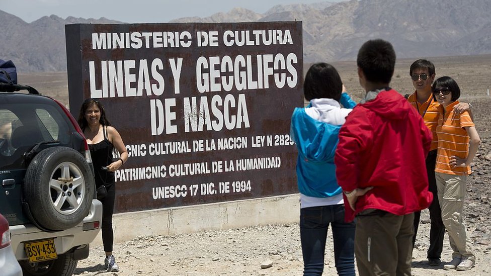 Las líneas y geoglifos de Nasca fueron declaradas patrimonio cultural de la humanidad por Unesco en 1994. Personas posando ante un cartel de Ministerio de Cultura antes de entrar a ver las líneas de Nasca.