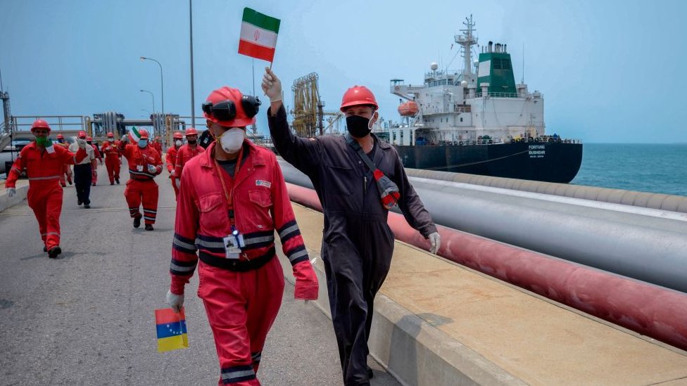Trabajadores petroleros venezolanos cargan con banderas de Irán y Venezuela.