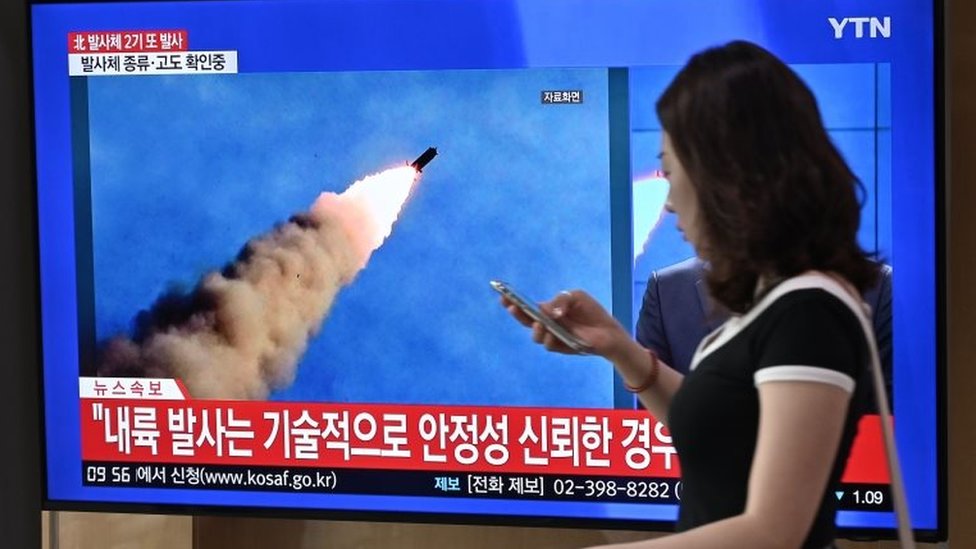 Женщина проходит мимо экрана телевизионных новостей, на котором видна запись запуска северокорейской ракеты на железнодорожном вокзале Сеула 10 сентября 2019 года.