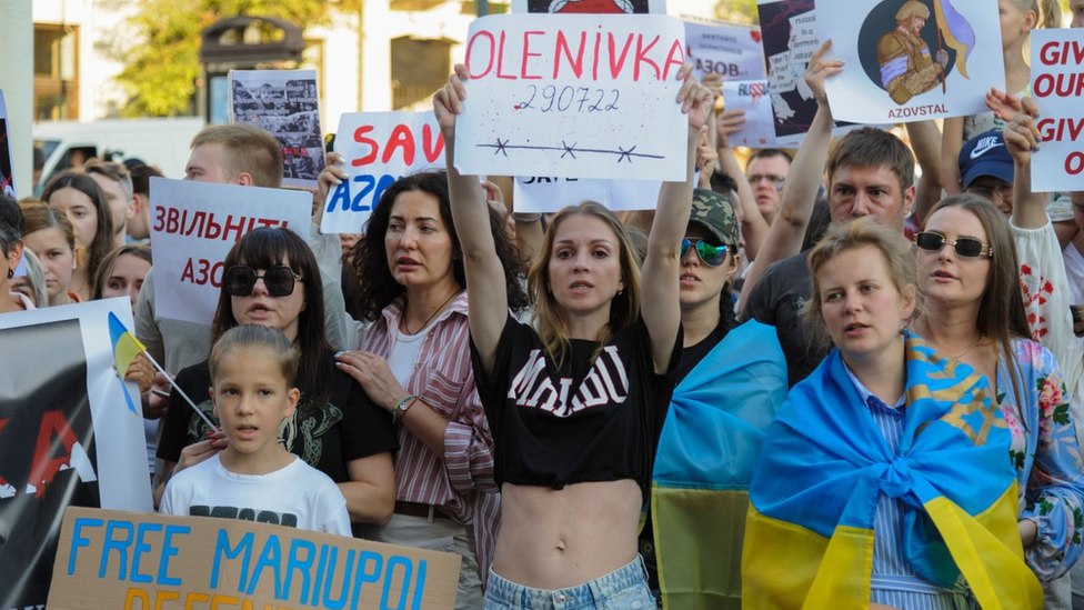Ukrainian protesters hold placards about Olenivka