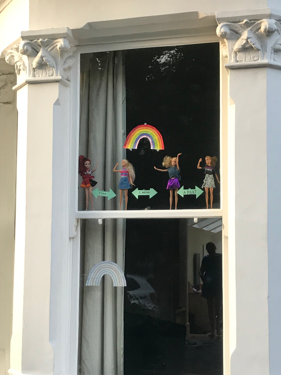 A row of Barbie dolls seen at a window.