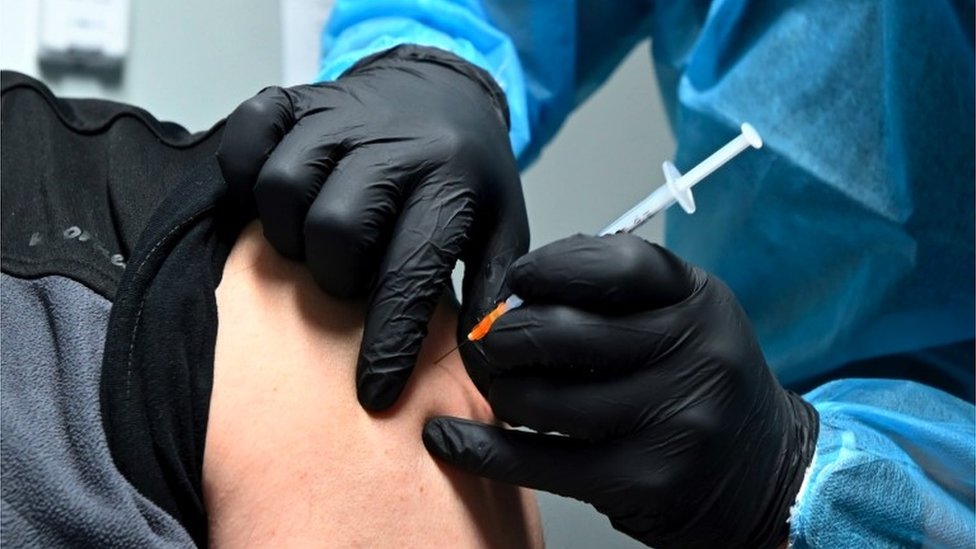 Un trabajador médico inyectando a una persona en el hombro.