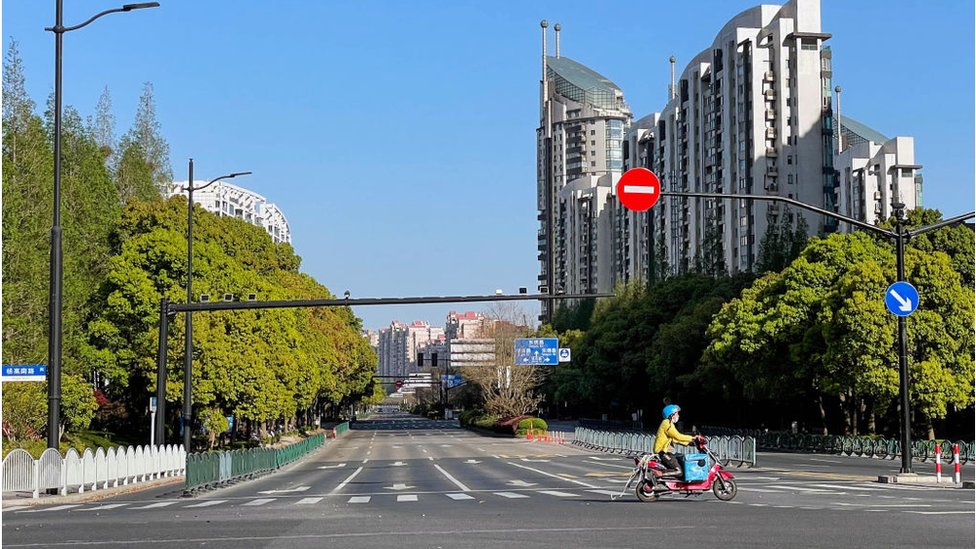 A food delivery rider passes an empty intersection in Pudong, Shanghai, China, On April 9, 2022. Shanghai is under lockdown
