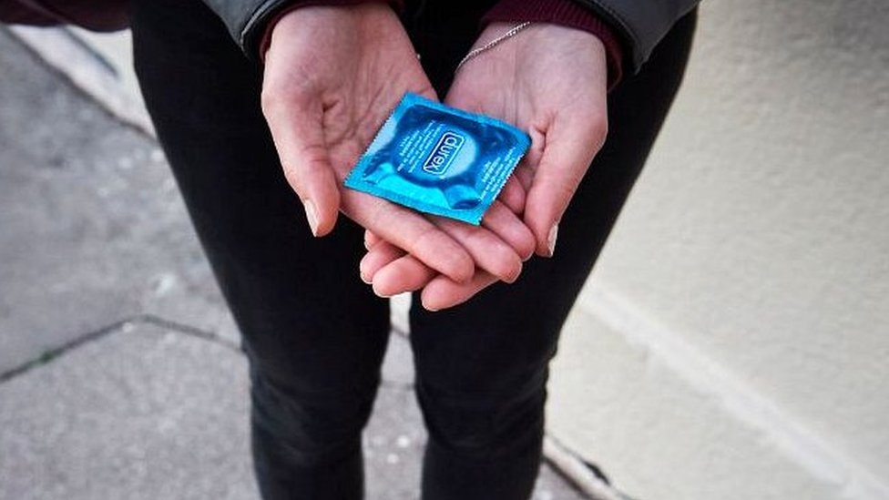 женщина, держащая презерватив