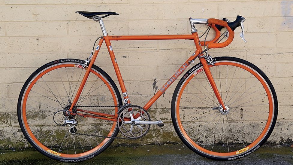 Tom Justice's bright orange racing bike leaning against a wall.