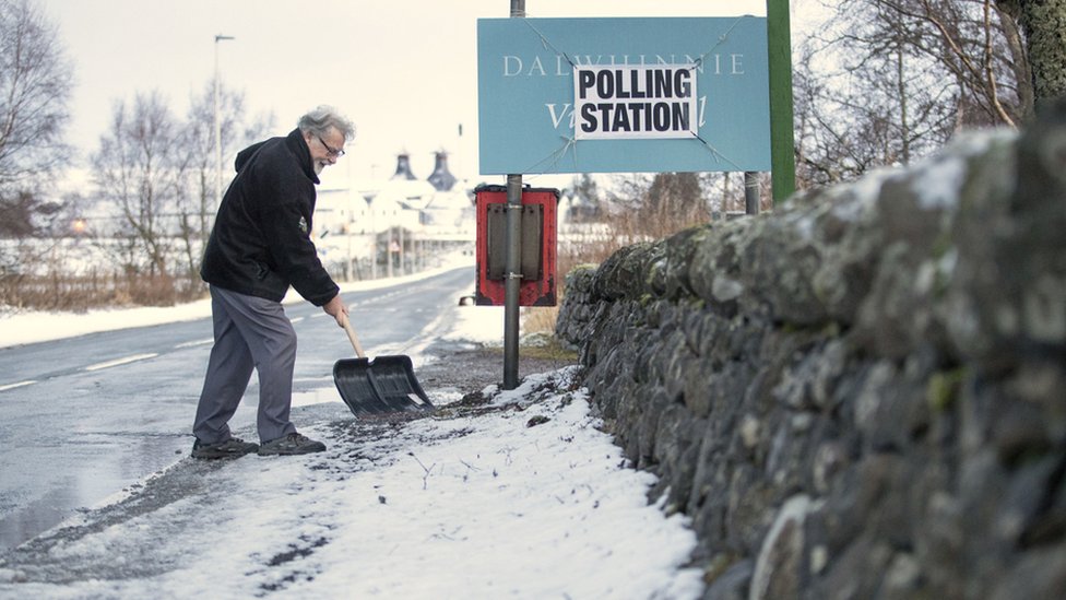 Мужчина убирает снег возле избирательного участка