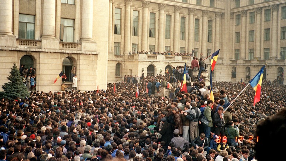 Protesters in Bucharest wave Romanian flags as they stage an anti-communist demonstration at Republic Square, 21 December 1989