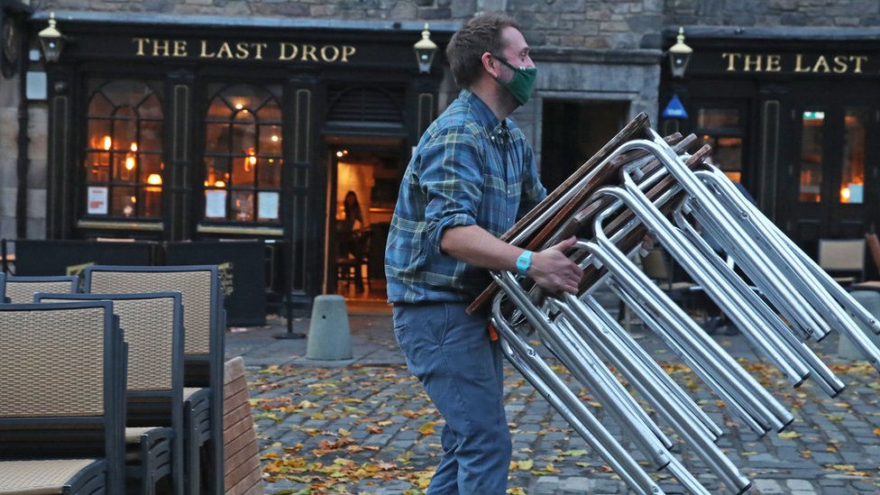 Pub worker stacking chairs in Edinburgh