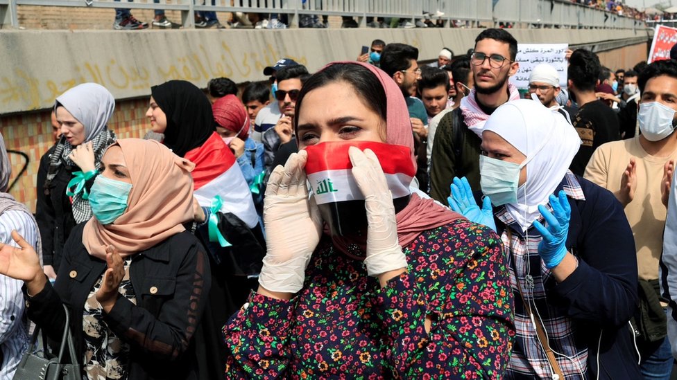 Протестующие в масках принимают участие в демонстрации в Международный женский день в Багдаде (8 марта 2020 г.)