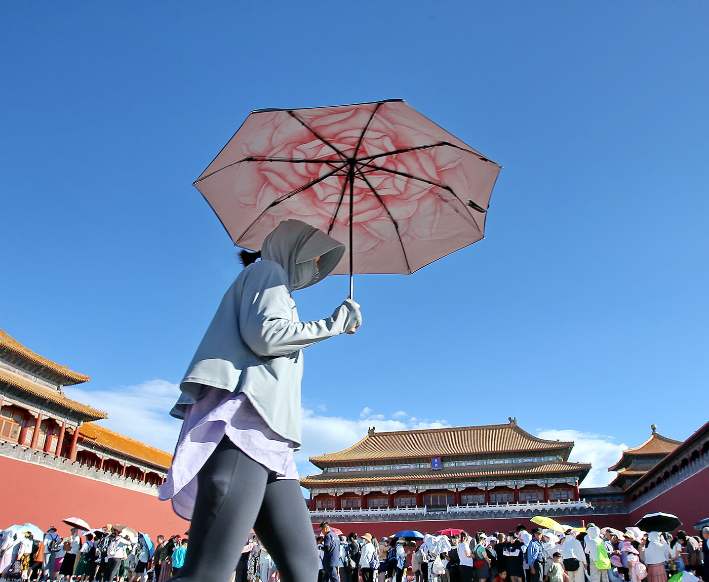 ​​A tourist shields herself from the sunshine with an umbrella while visiting the Palace Museum in Beijing - 9 July 2023