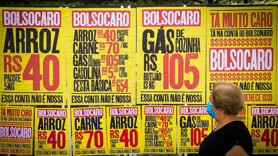 Idosa passa por cartazes da campanha 'Bolsocaro', que protesta contra a alta de preços no governo Bolsonaro