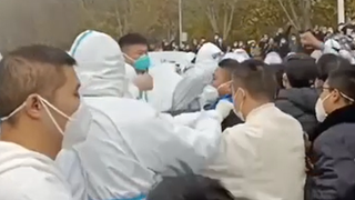 Protesters clash with security officers in hazmat suits during a protest march at the Foxconn factory site in Zhengzhou 23/11