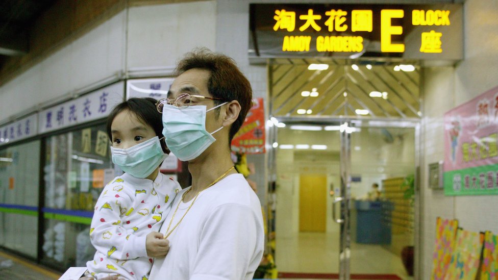 Мужчина держит ребенка возле квартала Сямэнь Гарденс в Гонконге в 2003 году