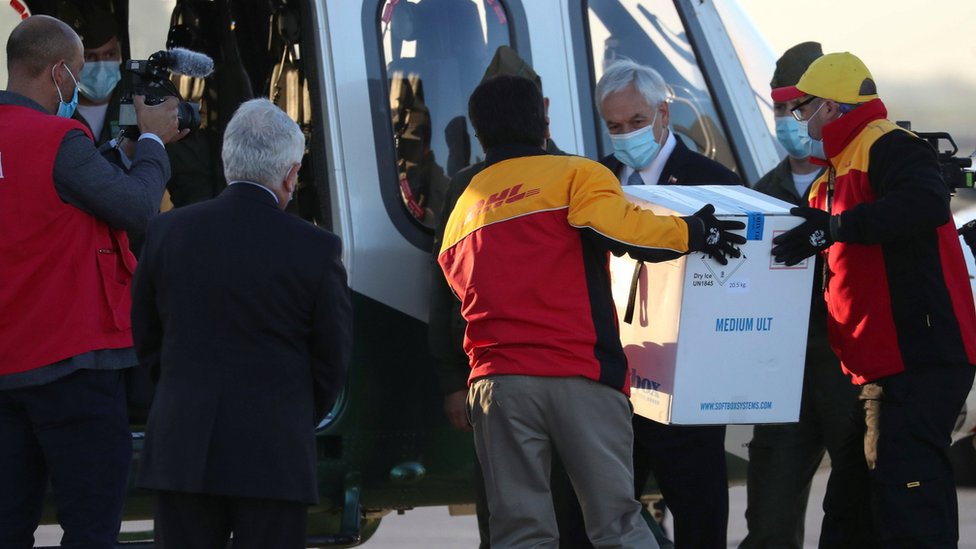 Chile's President Sebastián Piñera (centre-right) looks as workers carry the first batch of the Pfizer-BioNTech vaccine to a helicopter at Santiago's airport. Photo: 24 December 2020