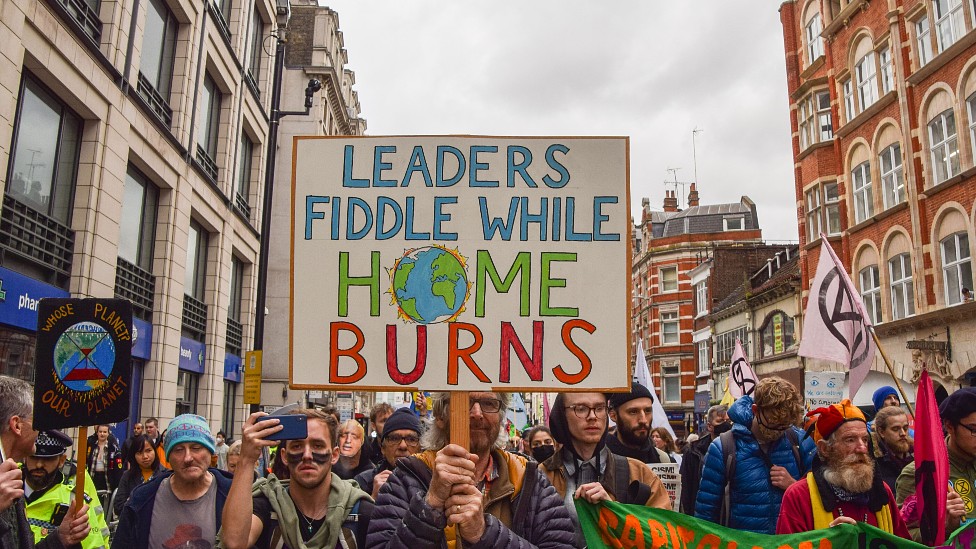 Manifestantes en Londres con un cartel que dice "mientras los políticos pretenden, nuestro hogar se está quemando".