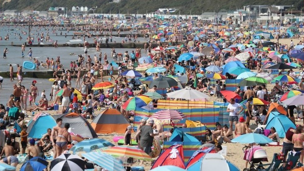 Люди наслаждаются жаркой погодой на пляже Борнмута в Дорсете
