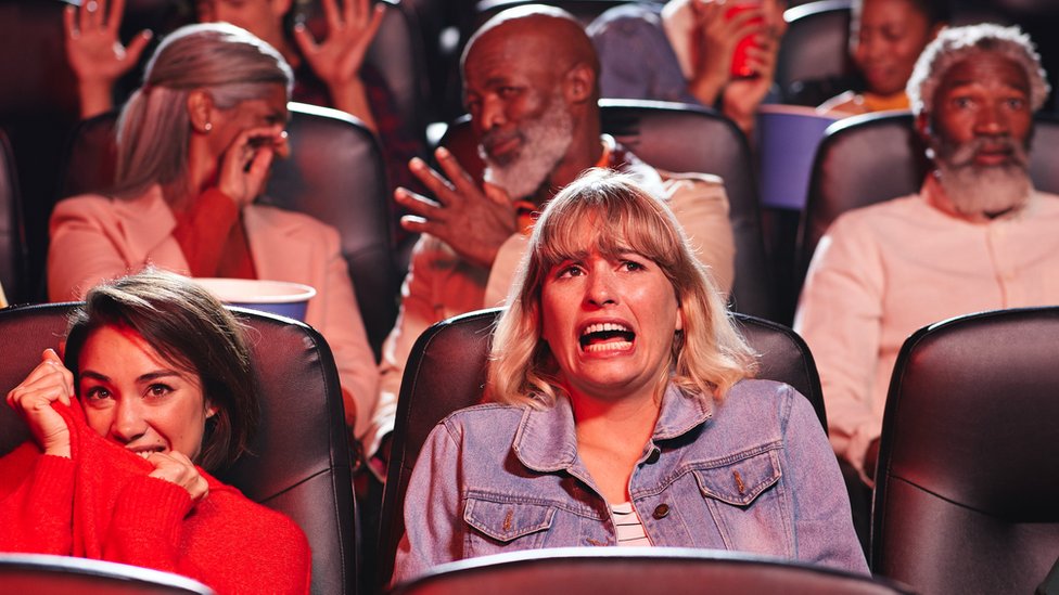 Una audiencia reaccionando a una película de terror en el cine.
