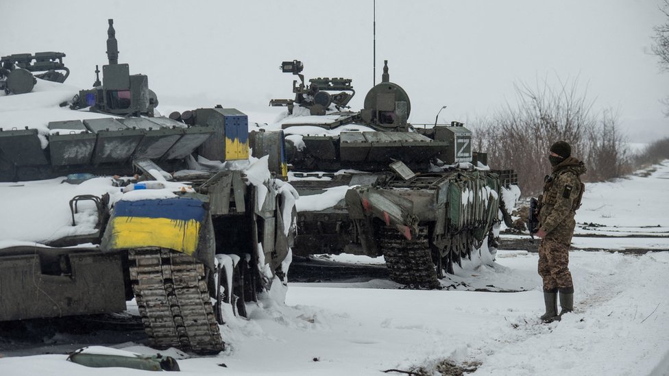 A Ukrainian serviceman stands near captured Russian tanks, one painted in the color of the Ukrainian national flag and the other marked with the letter ""Z"", amid the Russian invasion of Ukraine, in the north of the Kharkiv region, Ukraine March 4, 2022