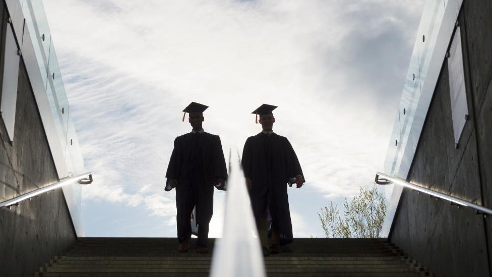 設計圖片：兩位大學畢業生在樓梯上往上走的倒影