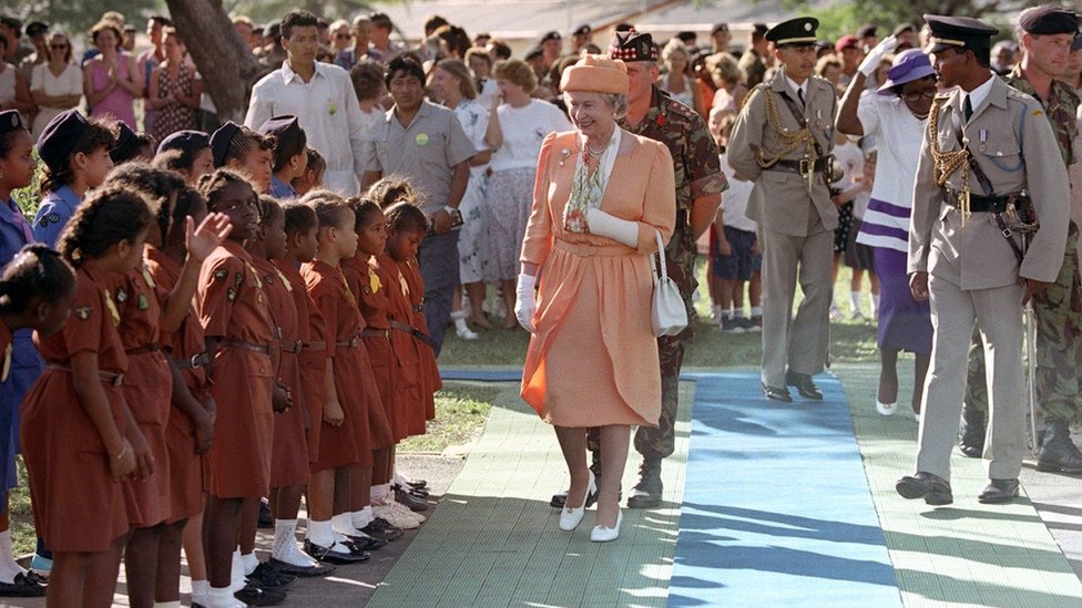 The Queen, pictured with a broken wrist, being greeted by a Brownie Pack when she arrived in Belize in 1994