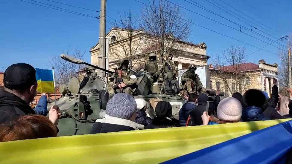 Pro-Ukrainian protesters pass Russian soldiers on a tank during a rally in Kherson in March, 2022