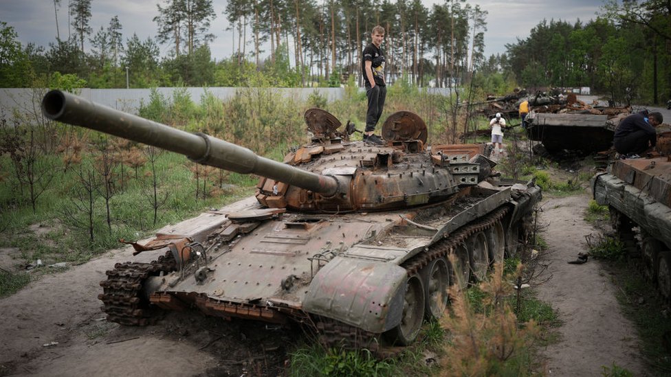 Personas revisando un tanque ruso abandonado cerca de Irpin.