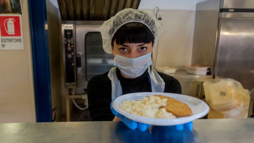 Voluntarios en Italia reparten comida a las personas que viven en la calle.