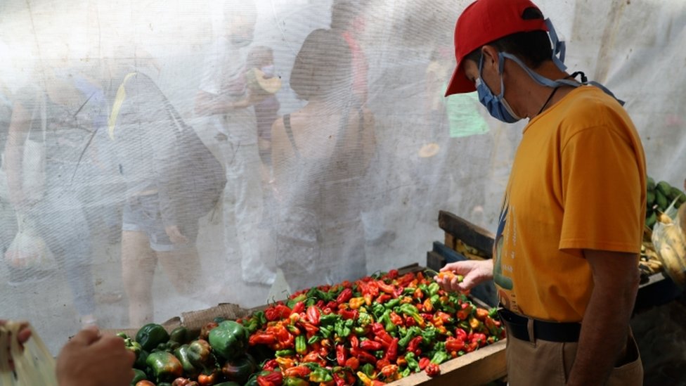 Personas comprando y haciendo fila en Venezuela para comprar alimentos.