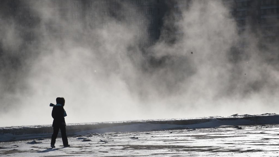 Una mujer caminando cerca del lago Michigan congelado.