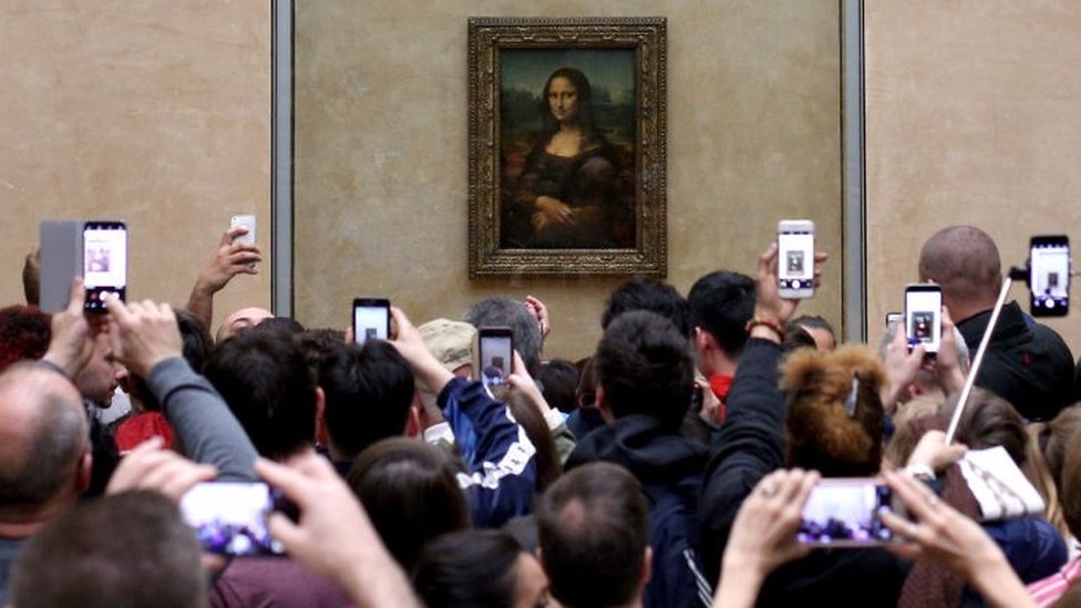 Visitantes toman fotos de la Mona Lisa de Leonardo Da Vinci, en el Museo del Louvre en París.
