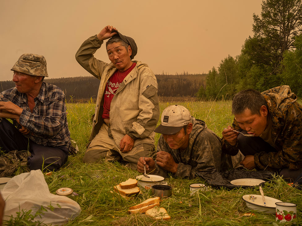 Voluntarios locales de extinción de incendios toman un descanso para comer en un campo en Magaras, en el centro de Sakha, Siberia, Rusia, el 1 de julio de 2021