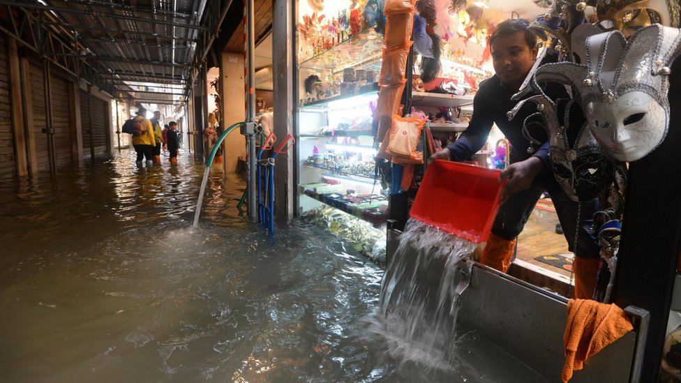 Shopkeeper empties water from his shop in Venice on 29 October 2018